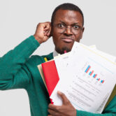 Dissatisfied black man prepares accounting report, holds papers with inforgraphic, wears spectacles for good vision, scratches head in bewilderment, isolated over white background. Income analysis